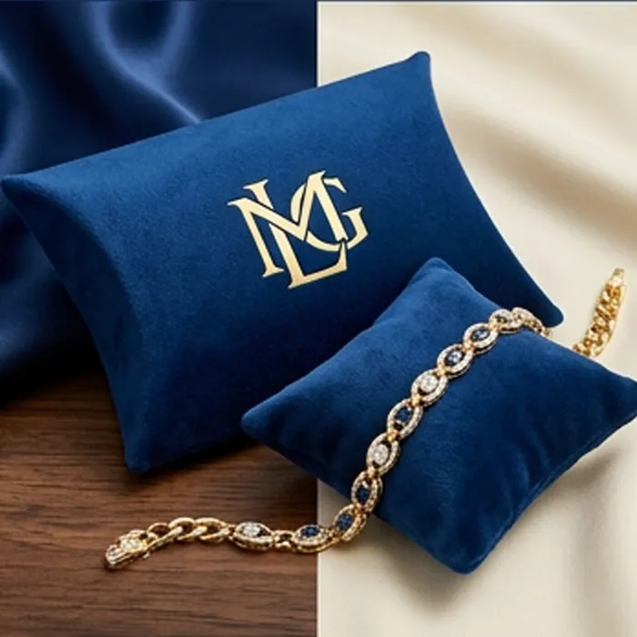 Navy bracelet pillow box with a gold monogram and a gold chain bracelet on a velvet cushion
