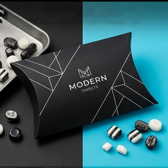 Black pillow box with monochrome sweets scattered on a teal surface