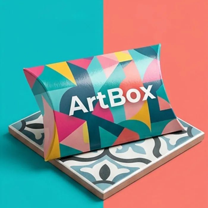 Brightly printed geometric cardboard pillow box on a patterned tile surface