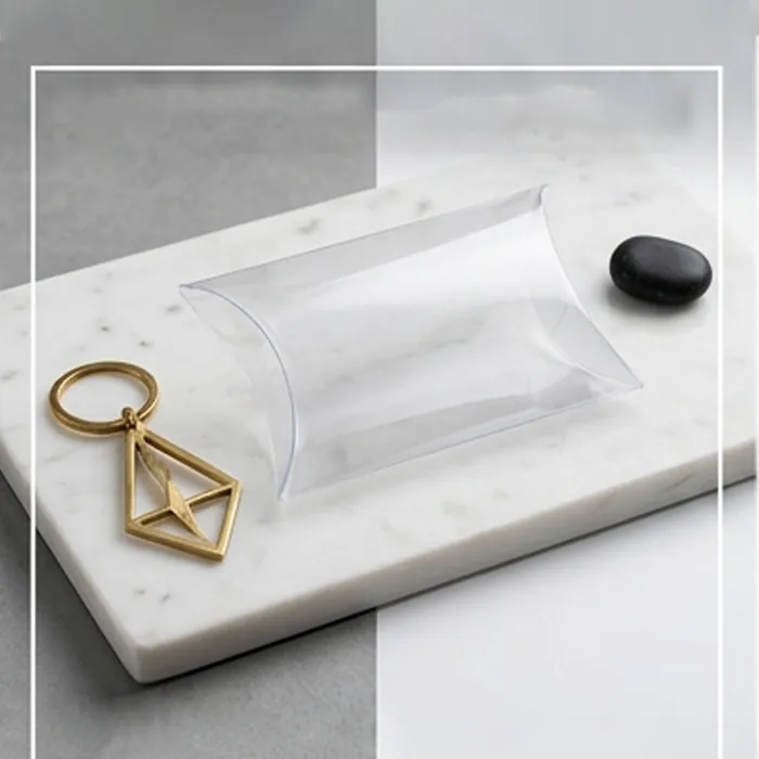 Empty clear pillow box on marble beside a gold keyring